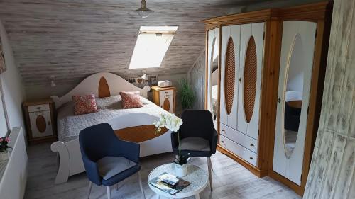 a small bedroom with a bed and two chairs at T.H.NY Village Inn Cottage in Tihany