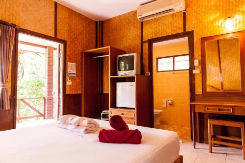 a bedroom with a bed and a tv and a television at Coco Palm Beach Resort - SHA Extra Plus in Mae Nam