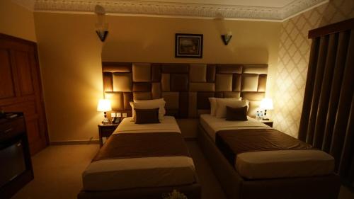 two beds in a hotel room with two lamps at World Inn by WI Hotel in Karachi