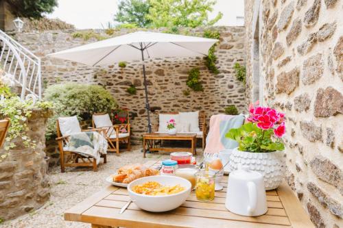 a table with food on a patio with an umbrella at Demeures & Châteaux - Hôtel De La Porte Saint-Malo in Dinan