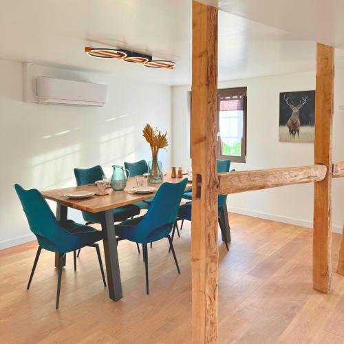 une salle à manger avec une table et des chaises bleues dans l'établissement Grand appartement chaleureux, à Steinbrunn-le-Bas