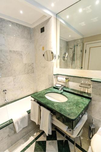 a bathroom with a sink and a large mirror at Art Hotel Commercianti in Bologna