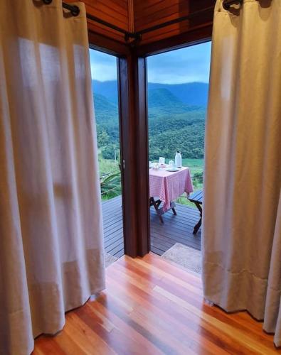 a room with a table and a view of the mountains at Chalé aconchegante com hidro no pé da serra in Orleans