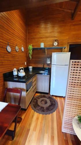 a kitchen with a white refrigerator and a table at Chalé aconchegante com hidro no pé da serra in Orleans