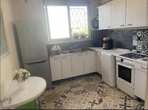 une cuisine avec des armoires blanches et une table à l'intérieur dans l'établissement T2 Vue Mer, à Cannes