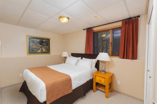 a bedroom with a bed and a table with a lamp at Overlander Mountain Lodge in Jasper