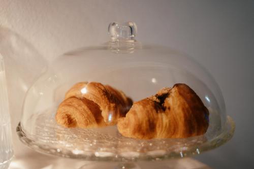 a glass dish with two croissants on it at VenuSuite VENOSA - Luxury House, Spa & Relax - in Venosa