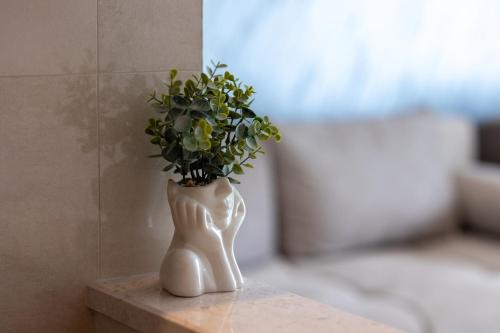 a white vase with a plant in it on a table at Apartmani Milos - Meljine in Herceg-Novi