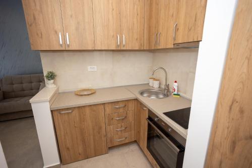 a small kitchen with wooden cabinets and a sink at Apartmani Milos - Meljine in Herceg-Novi