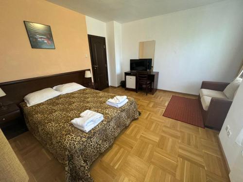 a room with a bed and a couch and a television at Villa Rila Borovets with Hot Pool, Jacuzzi & Sauna by BookVillaBG in Borovets