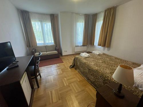 a bedroom with a bed and a desk and a television at Villa Rila Borovets with Hot Pool, Jacuzzi & Sauna by BookVillaBG in Borovets
