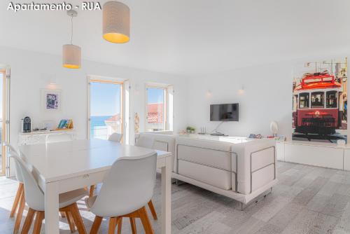 a white dining room with a white table and chairs at Season Apartments in Sesimbra