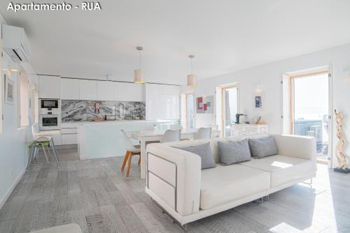 a white living room with a white couch and a table at Season Apartments in Sesimbra