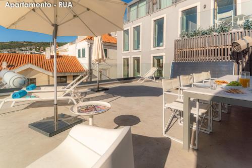 a patio with a table and chairs and an umbrella at Season Apartments in Sesimbra