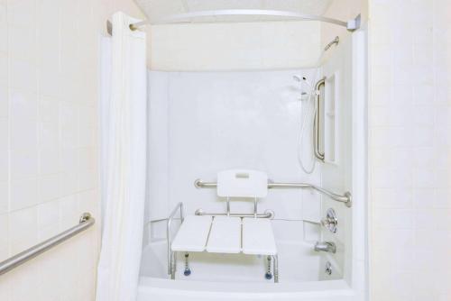 a white bathroom with a white chair in a shower at Super 8 by Wyndham Port Clinton in Port Clinton