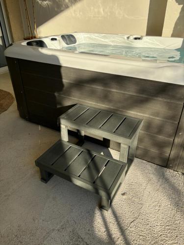 aption to a bed with a stool under it at Appartement cosy Quissac avec Jacuzzi in Quissac