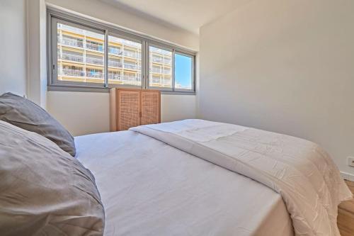 un lit blanc dans une chambre avec deux fenêtres dans l'établissement Spacieux T3 en front de mer, à Sainte-Maxime