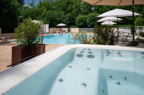 a swimming pool with a jacuzzi tub in a resort at Logis Hôtels - Hôtel Restaurant Domaine Les Falaises in Martel