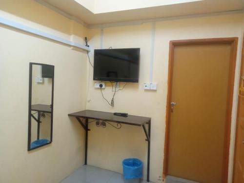a room with a television on a wall with a table at Hotel Bajet Gaya Warisan in Kota Bharu