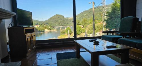 a living room with a table and a large window at Casa da Mila in Rio Caldo