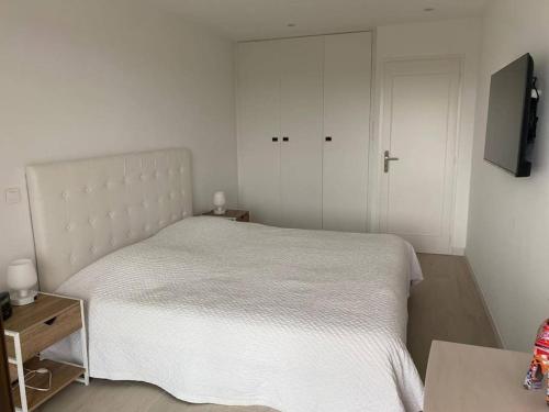 une chambre avec un lit blanc et une télévision à écran plat dans l'établissement 14471 Location meublée 2 pièces, à Mandelieu-la-Napoule