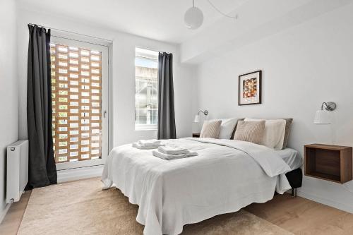 a white bedroom with a bed and a window at Beautiful City Center Apartment w Balcony in Aarhus