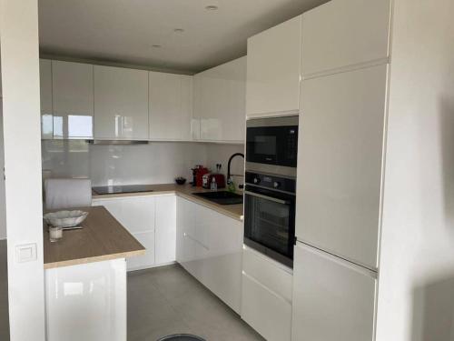 une cuisine blanche avec des armoires et des appareils blancs dans l'établissement 14471 Location meublée 2 pièces, à Mandelieu-la-Napoule