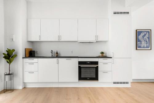 a white kitchen with white cabinets and a black oven at Beautiful City Center Apartment w Balcony in Aarhus