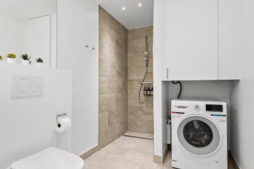 a white bathroom with a washing machine in a bathroom at Beautiful City Center Apartment w Balcony in Aarhus