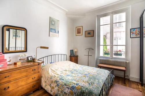 une chambre avec un lit, une commode et un miroir dans l'établissement Vintage 2BD Apartment with Patio in Montmartre, à Paris