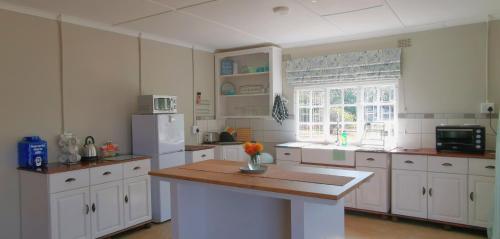 a kitchen with white cabinets and a wooden counter top at Weltevreden Cottage at Ngweni Private Game Farm in Hluhluwe