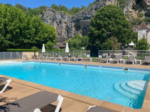 a swimming pool with chairs and a mountain in the background at Logis Hôtels - Hôtel Restaurant Domaine Les Falaises in Martel