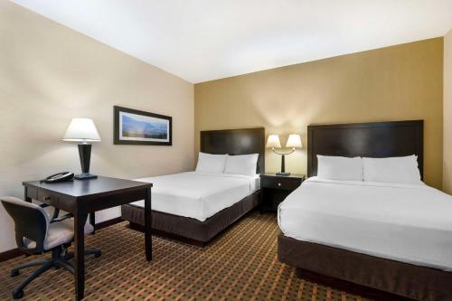 a hotel room with two beds and a desk with a computer at Best Western Pacific Inn in Vernon