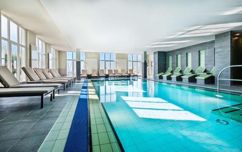 a pool in a hotel with chairs and tables at Lindner Hotel Boltenhagen, part of JdV by Hyatt in Boltenhagen