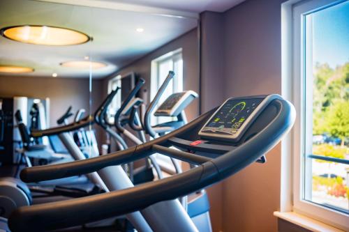 a row of treadmills in a gym with a cell phone at Lindner Hotel Boltenhagen, part of JdV by Hyatt in Boltenhagen