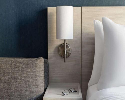 a lamp with a pair of glasses on a table next to a bed at Hyatt Place New York Chelsea in New York