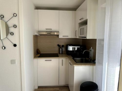 une petite cuisine avec des armoires blanches et un micro-ondes dans l'établissement Studio cabine en étage, front de mer, à Fréjus