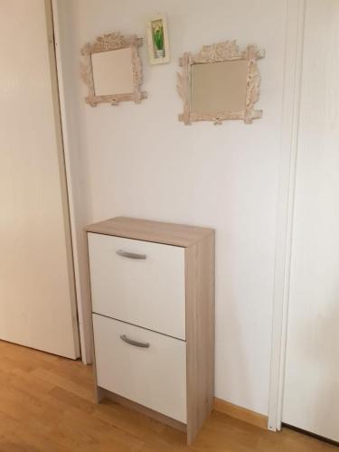 - une commode dans une pièce avec deux miroirs sur le mur dans l'établissement Soleil 65, à Bagnères-de-Bigorre