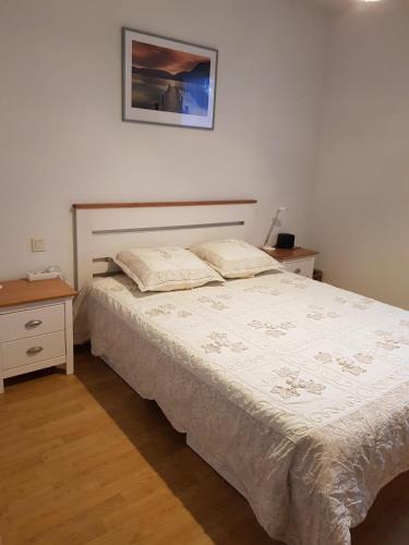 une chambre avec un lit et deux tables et une photo sur le mur dans l'établissement Soleil 65, à Bagnères-de-Bigorre