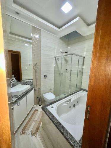 a bathroom with a tub and a sink and a toilet at Casa Familiar Locação Semanal Maringa in Maringá