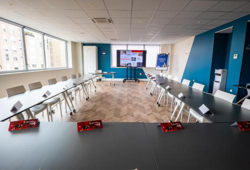 a conference room with tables and chairs and a screen at ibis Dijon Gare in Dijon