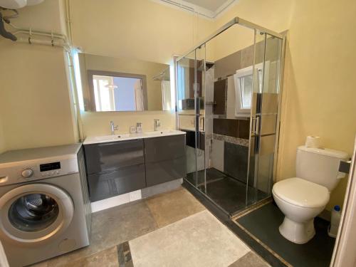 a bathroom with a toilet sink and a washing machine at Résidence Verdi - Appartements meublés en centre ville in Bédarieux