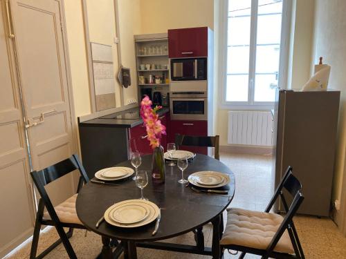 a kitchen with a black table with chairs and a table sidx sidx sidx at Résidence Verdi - Appartements meublés en centre ville in Bédarieux