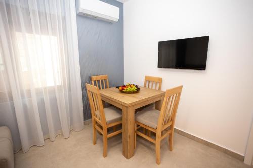 a dining room table with two chairs and a television at Apartmani Milos - Meljine in Herceg-Novi