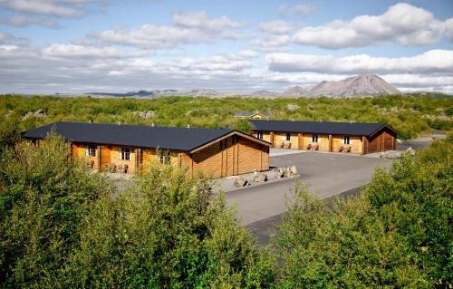 two wooden buildings in a field with a mountain in the background at Vogafjós Farm Resort in Myvatn