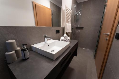 a bathroom with a white sink and a shower at Self Service Hotel Schnalser Hof in Naturno