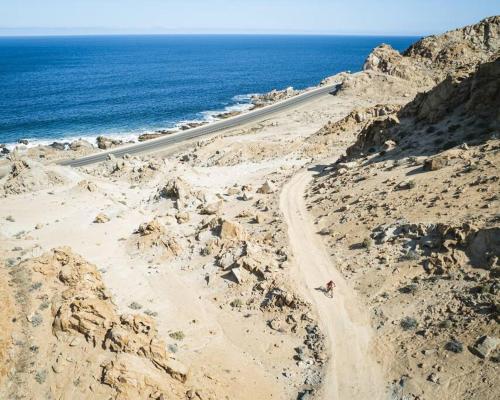 a road on the side of a mountain next to the ocean at Cabañas Alto Rincon de Atacama in El Barquito