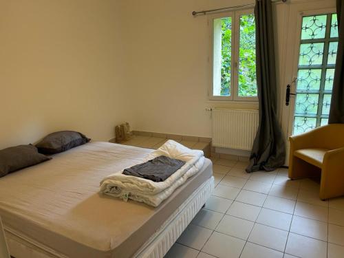 a bedroom with a bed and a chair and a window at Maison de ville arborée avec cachet in Nanterre