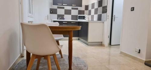 - une cuisine avec une table en bois et une chaise blanche dans l'établissement Appartement de la Richelandiere, à Saint-Étienne