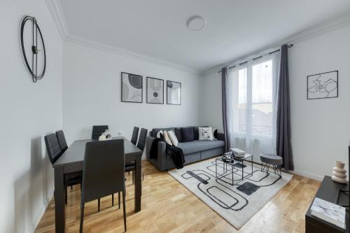 a living room with a table and a couch at Maison 8 personnes - Parking - Métro 7 et Rer B à 6 minutes in La Courneuve